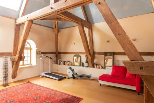 a living room with a red couch and a treadmill at CHATEAU du PERRAY in Saint-Mars-du-Désert