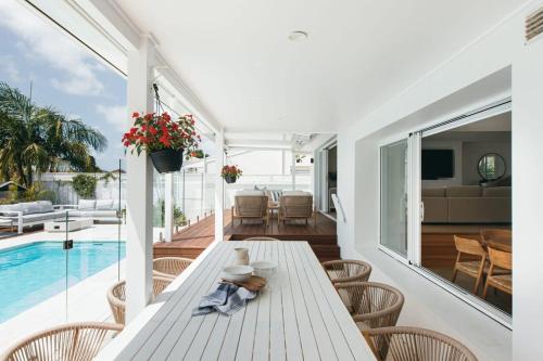 a white dining room with a table and a pool at MainSail by Coast Hosting in Daleys Point