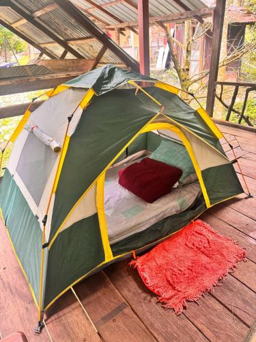 a green and yellow tent sitting on a wooden floor at Devalley Basecamp in Kampong Ulu Dong