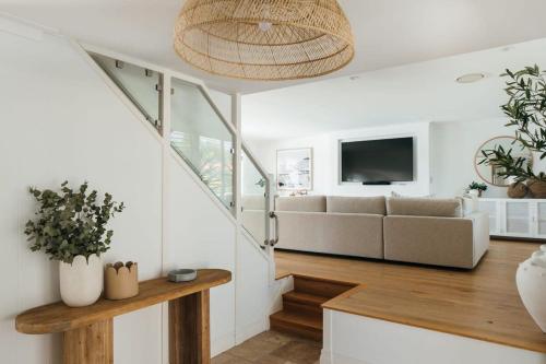 a living room with a couch and a television at MainSail by Coast Hosting in Daleys Point