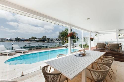 a dining room with a table and chairs and a pool at MainSail by Coast Hosting in Daleys Point