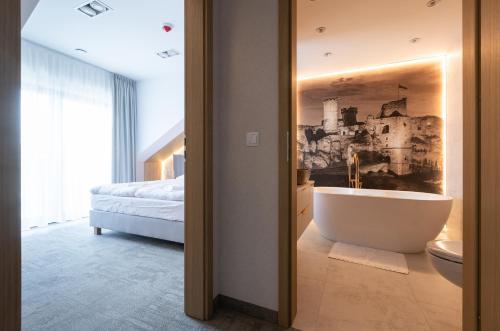 a bathroom with a tub and a bedroom with a bed at Przystań Marywil in Żarki