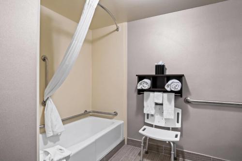 a bathroom with a bath tub and a chair at Comfort Inn in Cadillac