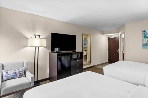 a hotel room with a bed and a chair and a television at Comfort Inn in Cadillac