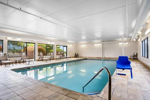 a swimming pool with blue chairs and tables at Comfort Inn in Cadillac