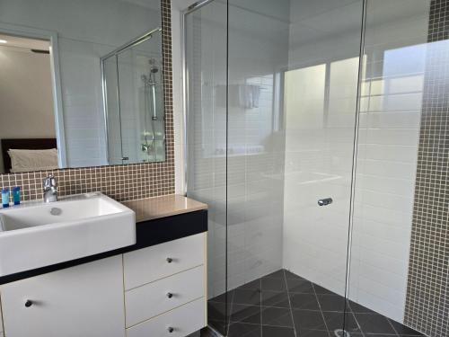 a bathroom with a sink and a glass shower at Quarterdecks Retreat in Hervey Bay