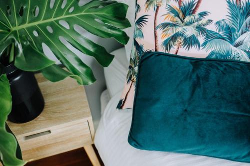 a green pillow sitting on a bed next to a plant at Palm House by Coast Hosting in Terrigal