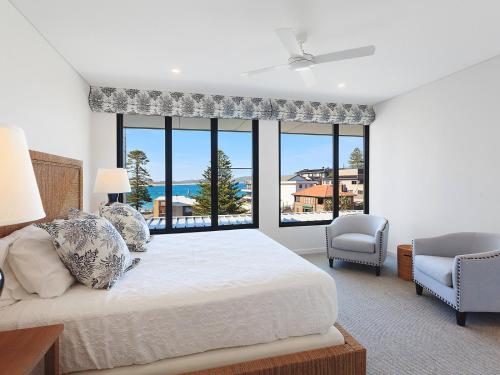 een slaapkamer met een bed en een groot raam bij PineTree Penthouse by Coast Hosting in Terrigal
