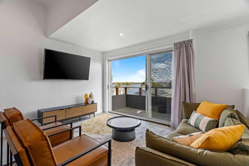 a living room with a couch and a tv at Retro Lake Vista By Coast Hosting in Budgewoi