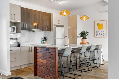 a kitchen with white cabinets and a island with bar stools at Retro Lake Vista By Coast Hosting in Budgewoi