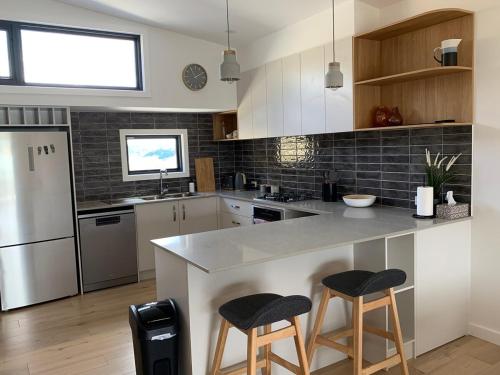 a kitchen with a counter and two bar stools at Flow Rider #6 in Jindabyne