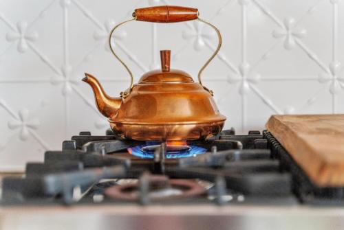 a tea kettle sitting on top of a stove at Cosy Family Farm Stay - Daily Animal Feeding in Wamberal