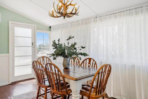 a dining room table with chairs and a vase with a plant at Cosy Family Farm Stay - Daily Animal Feeding in Wamberal