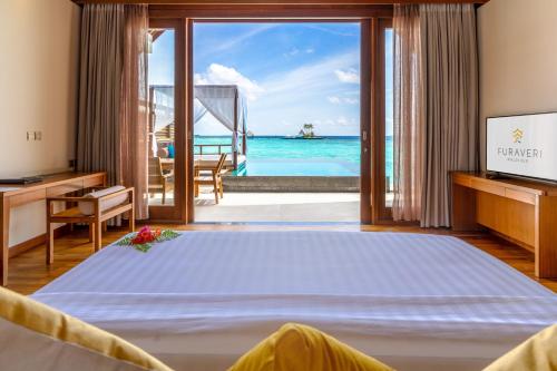 a bedroom with a bed and a view of the ocean at Furaveri Maldives - COMPLIMENTARY ROUND-TRIP SEAPLANE TRANSFER for two for a minimum of 5 nights or more from May 1st to October 31st, 2025 in Raa Atoll