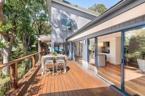 a wooden deck with a table and chairs on it at Serenity at Macs by Coast Hosting in Macmasters Beach