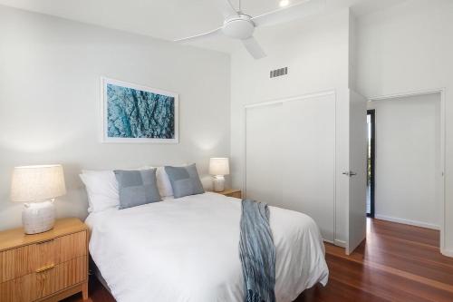 a bedroom with a white bed and a ceiling fan at Serenity at Macs by Coast Hosting in Macmasters Beach