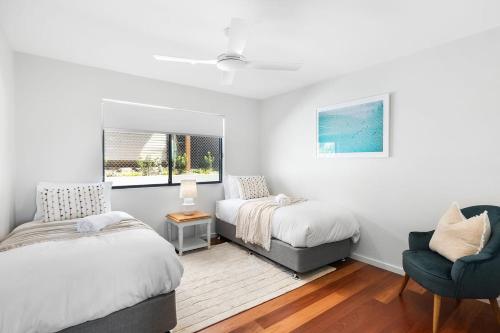 a bedroom with two beds and a chair at Serenity at Macs by Coast Hosting in Macmasters Beach