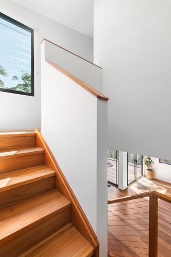 a staircase in a house with white walls and wooden floors at Serenity at Macs by Coast Hosting in Macmasters Beach