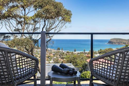 a balcony with two chairs and a view of the ocean at The Glass House by Coast Hosting in Copacabana