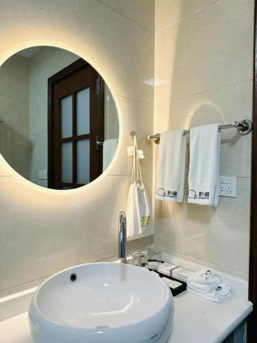 a bathroom with a white sink and a mirror at Gui zhou Wan Feng Lin Eave Boutique Hotel in Nahui