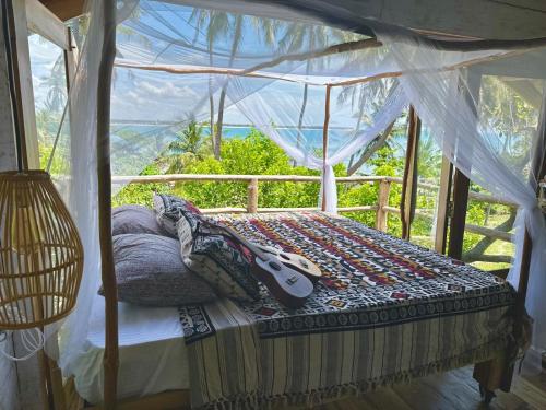 une chambre avec un lit avec une guitare dessus dans l'établissement The Tree House, à Baie d'Arugam