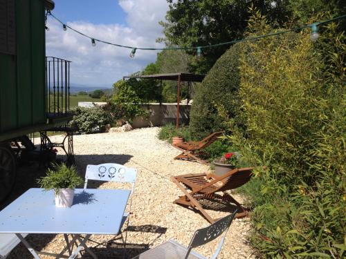 einen Garten mit Stühlen, einem Tisch und einer Bank in der Unterkunft Une roulotte à la campagne in Saint-Just-et-Vacquières