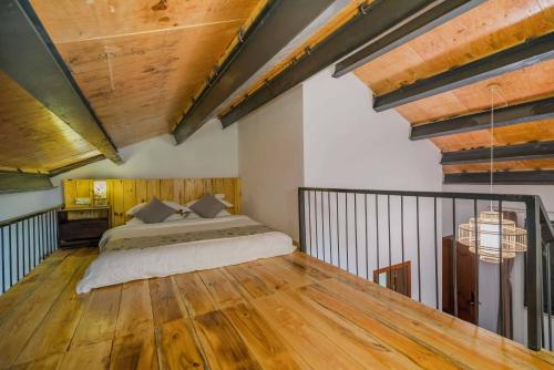 a bedroom with a bed and a wooden floor at Gui zhou Wan Feng Lin Eave Boutique Hotel in Nahui