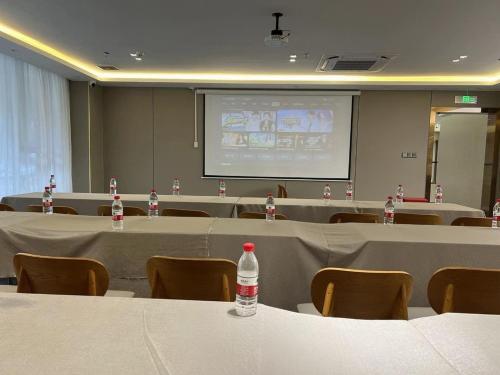 a conference room with tables and chairs and a screen at ParkHeng Hotel Shenzhen World Exhibition & Convention Center Branch in Shenzhen