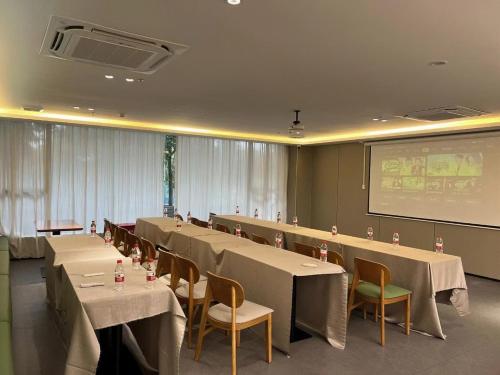 a conference room with tables and chairs and a screen at ParkHeng Hotel Shenzhen World Exhibition & Convention Center Branch in Shenzhen