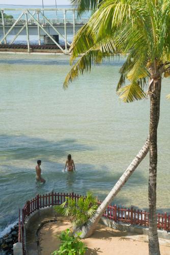 two men are in the water near a palm tree at Shalza Ahangama in Ahangama