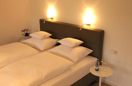 two beds with white pillows sitting next to a table at Landhotel Adler in Sigmarszell