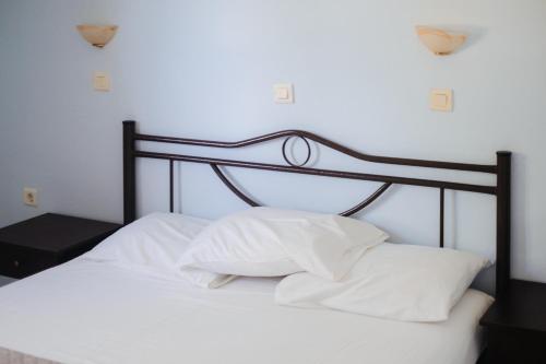 a bed with white pillows and a black head board at Finikas Apartments in Plakias