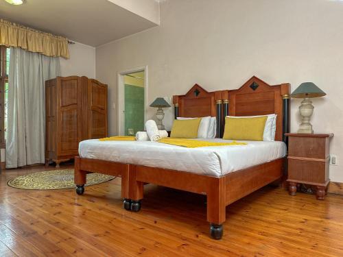 a bedroom with a large wooden bed with yellow pillows at Park Gables Loftus Guest House in Pretoria