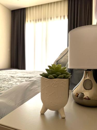 a plant in a pot on a table next to a lamp at Lilly Lagoon Townhouse in Ţāqah