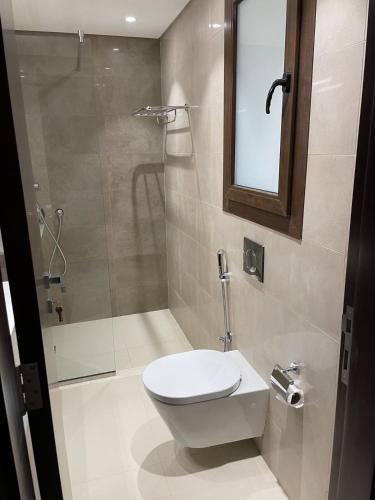 a bathroom with a toilet and a shower at Lilly Lagoon Townhouse in Ţāqah