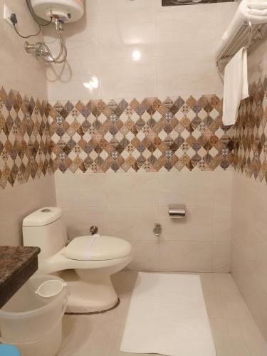 a white bathroom with a toilet and a sink at New Orange Tree Classic Fall in Mussoorie with pool & parking in Mussoorie