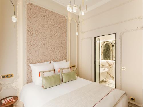 une chambre avec un grand lit blanc et un miroir dans l'établissement Merveil - Signature Suite-Champs Elysees- Marignan, à Paris