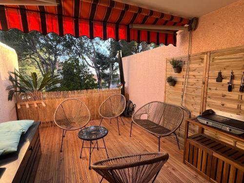 une terrasse avec trois chaises, une table et un lit dans l'établissement Confort et évasion à l'Almanarre, à Hyères