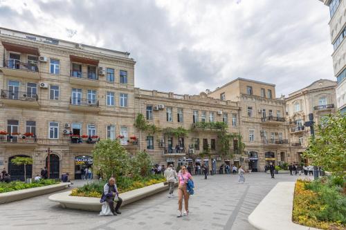 people walking in a plaza in front of a large building at Nizami Central Park Hotel in Baku