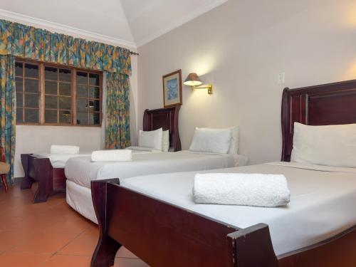 a hotel room with three beds and a window at Park Gables Loftus Guest House in Pretoria