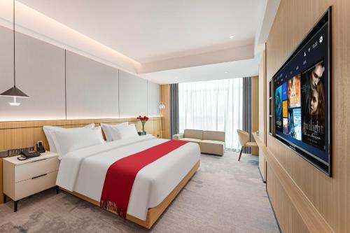 a hotel room with a bed and a flat screen tv at ParkHeng Hotel Shenzhen World Exhibition & Convention Center Branch in Shenzhen