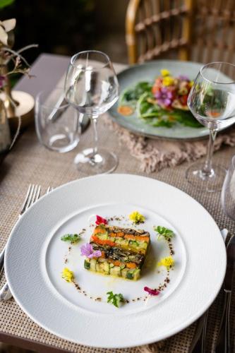 a plate of food on a table with wine glasses at LA FERME DE LA HUPPE in Gordes