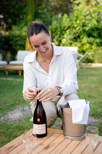 a woman sitting at a table looking at a bottle of wine at LA FERME DE LA HUPPE in Gordes
