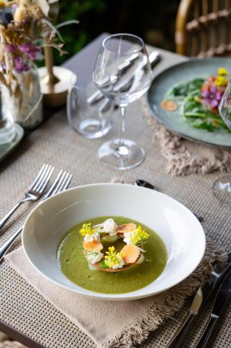 a white plate of soup on a table with a glass at LA FERME DE LA HUPPE in Gordes