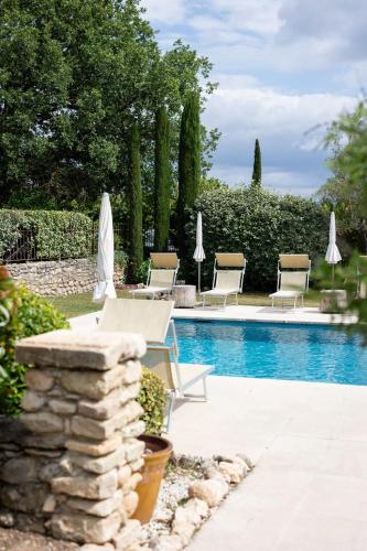 a pool with chairs and umbrellas next to at LA FERME DE LA HUPPE in Gordes