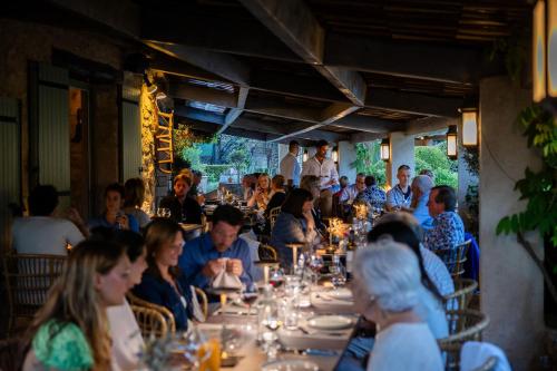 a group of people sitting at tables in a restaurant at LA FERME DE LA HUPPE in Gordes