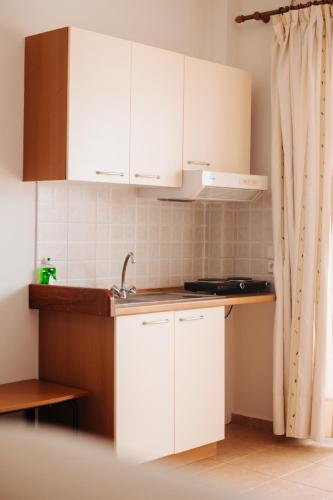 a kitchen with white cabinets and a sink at Finikas Apartments in Plakias