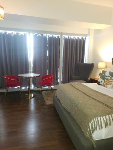 a bedroom with a bed and two red chairs and a table at Aeon Towers Luxury Suites in Davao City