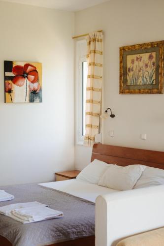 a white bedroom with a bed and a window at Finikas Apartments in Plakias