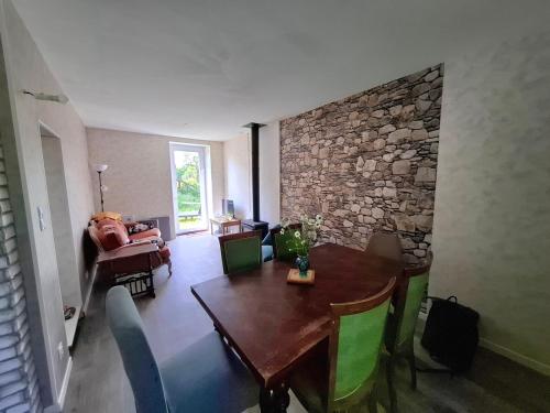 a living room with a wooden table and a stone wall at Maison de vacances à la campagne in Les Grands Chézeaux
